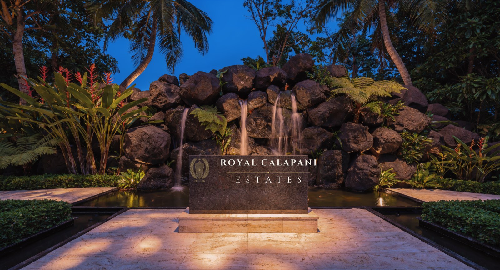 Artist's impression of the estate entrance at dusk: water falling over stacked
            volcanic boulders behind a dark name stone reading Royal Calapani Estates.