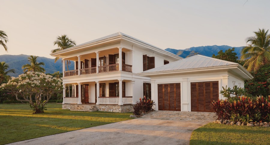 Artist's impression of the Gallery: a white West Indies colonial house
                  with double galleries, dark louvered Bahama shutters, a pale pyramidal
                  metal roof and an enclosed garage in the end wing.